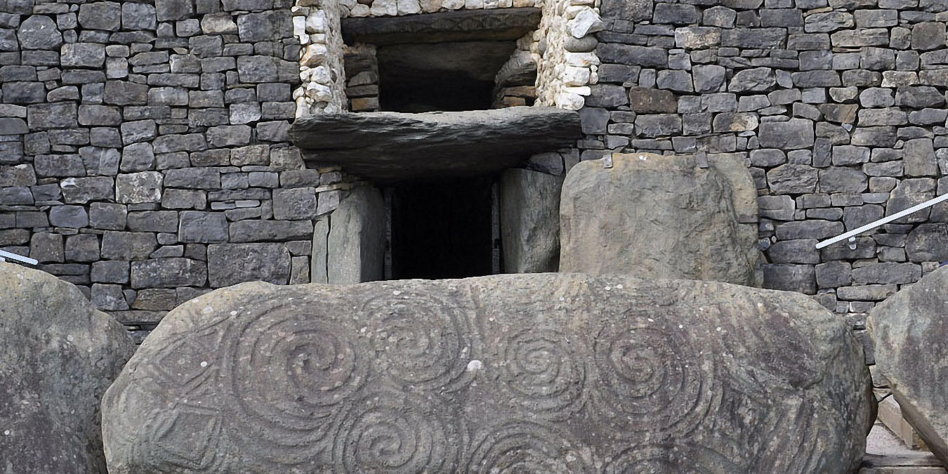 Newgrange : la pierre gravée de spirales devant l’entrée. Au-dessus de l’entrée, la roof-box